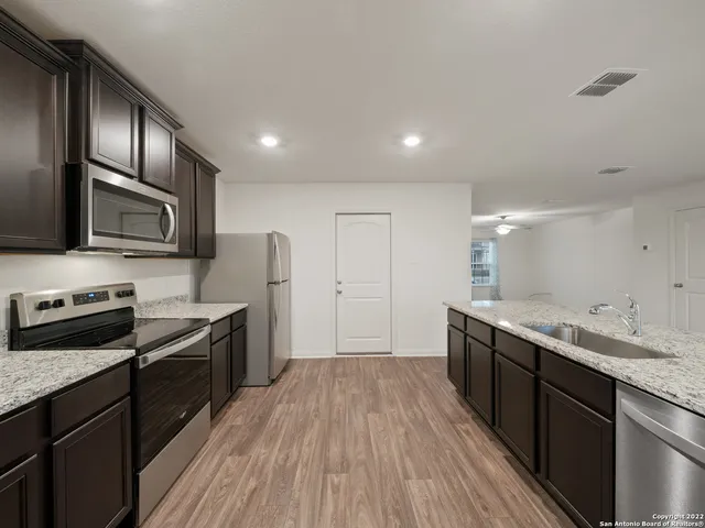 a kitchen with a sink wooden floor and stainless steel appliances
