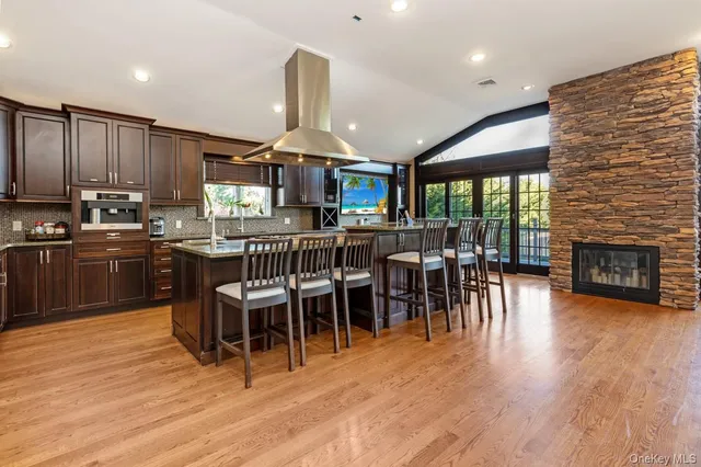 a view of a kitchen with kitchen island granite countertop wooden floors and a view of living room
