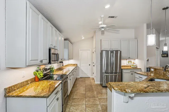 a kitchen with stainless steel appliances granite countertop a refrigerator a stove and a sink