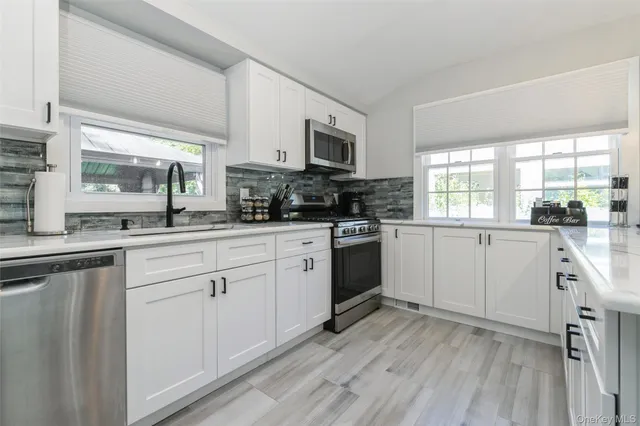 a kitchen with white cabinets sink and appliances