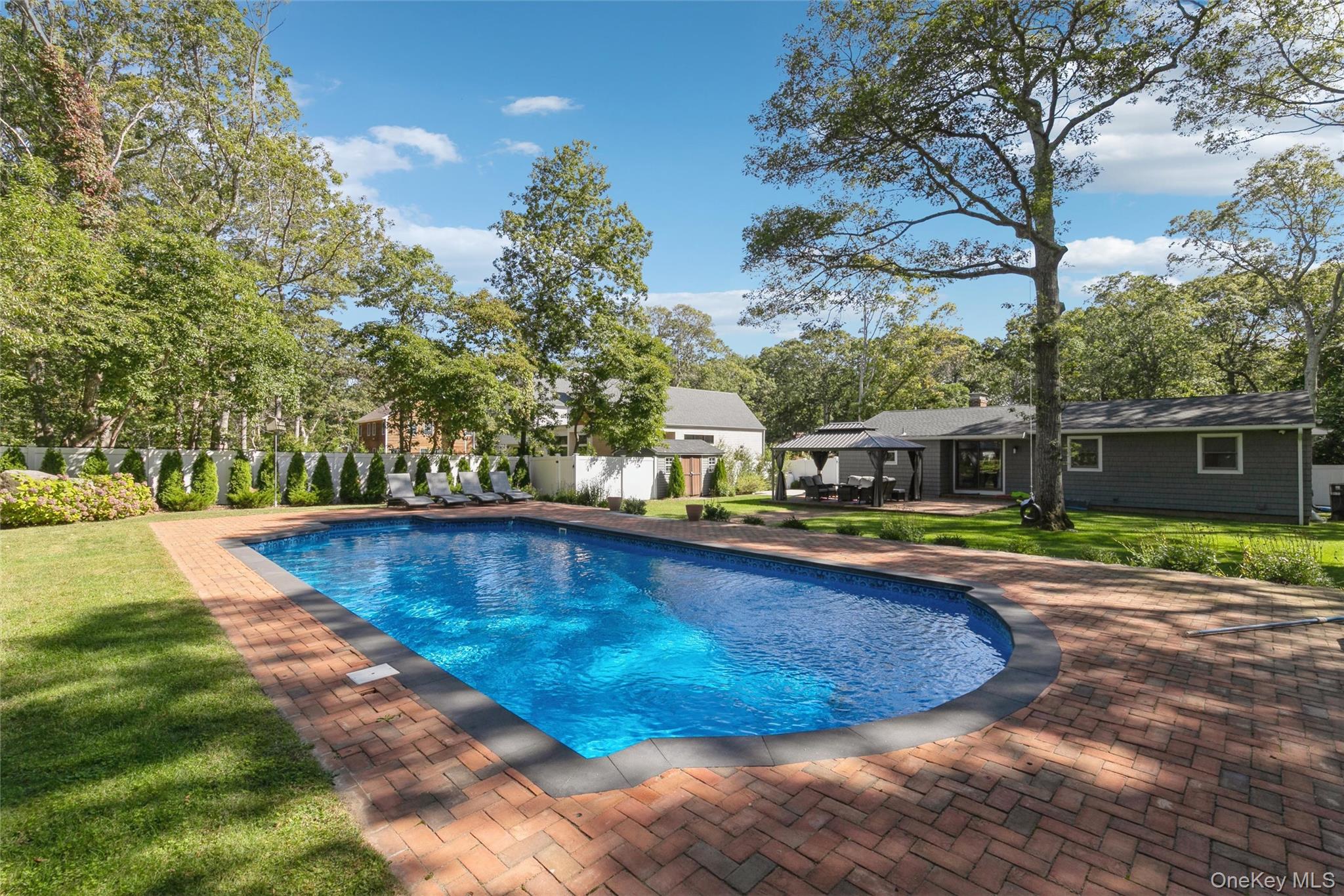 10 Rutland Road East Hampton, NY 11937 - Photo 35 of 47 a view of swimming pool with outdoor seating and trees in the background