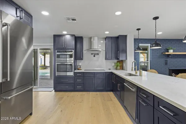 a large kitchen with stainless steel appliances kitchen island granite countertop a refrigerator a oven and a sink