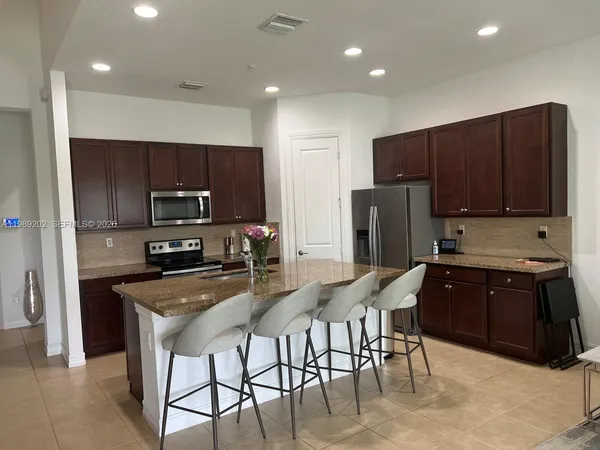 a kitchen with stainless steel appliances granite countertop a refrigerator a stove a sink a microwave a dining table and chairs