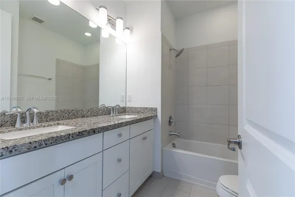 a bathroom with a granite countertop sink a toilet and shower