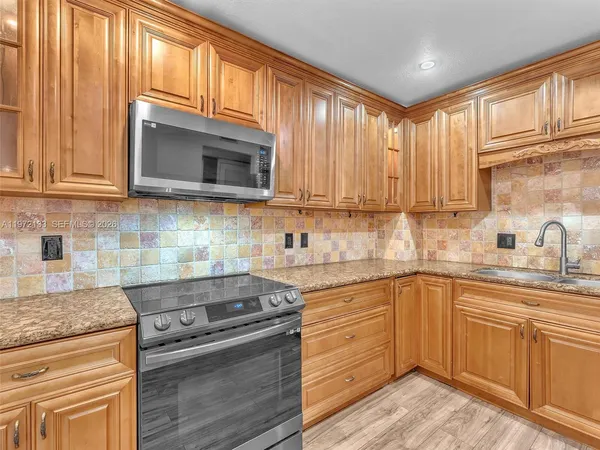 a kitchen with stainless steel appliances granite countertop a stove sink microwave and cabinets