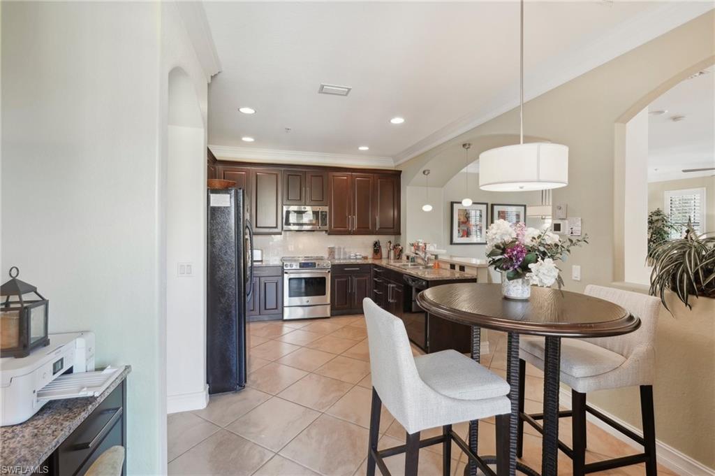 9108 Capistrano Street South, Unit 7401 Naples, FL 34113 - Photo 11 of 44 a kitchen with stainless steel appliances a dining table chairs and sink