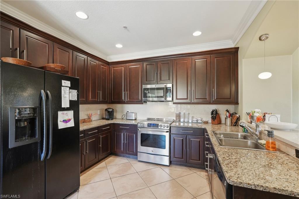 9108 Capistrano Street South, Unit 7401 Naples, FL 34113 - Photo 13 of 44 a kitchen with stainless steel appliances granite countertop wooden cabinets a sink and dishwasher