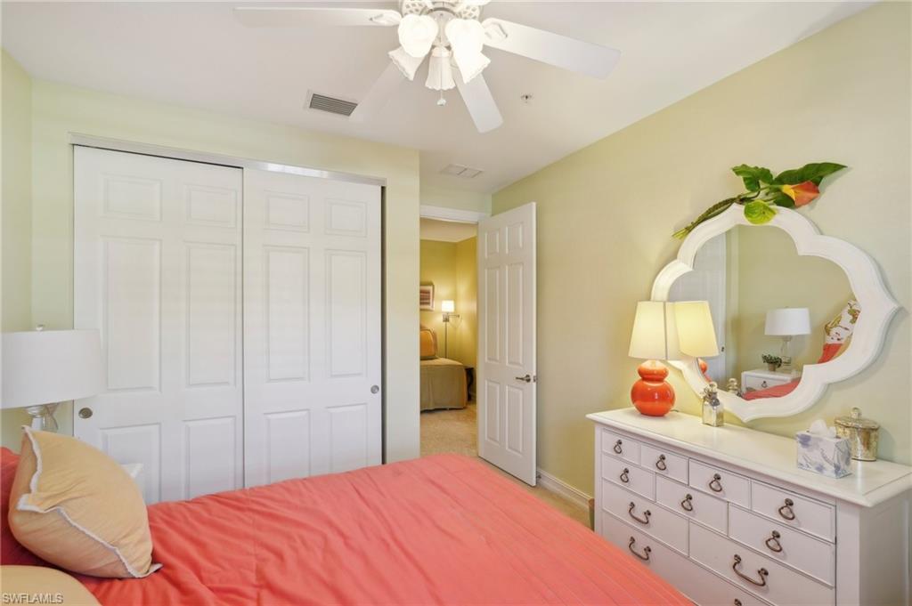 9108 Capistrano Street South, Unit 7401 Naples, FL 34113 - Photo 29 of 44 a bedroom with a bed a mirror on dresser and a chandelier