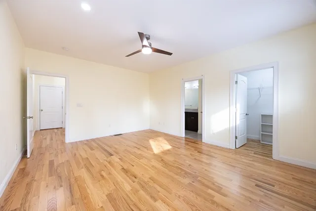 a view of empty room with wooden floor and ceiling fan