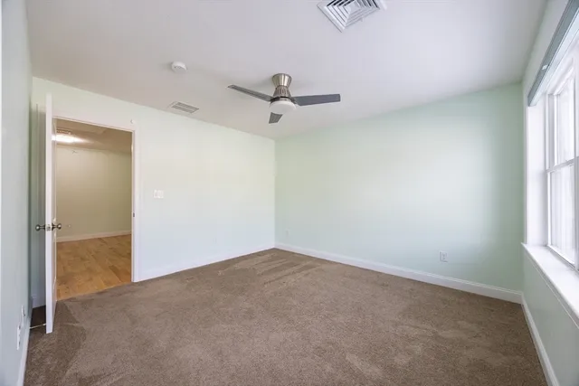 an empty room with windows and fan