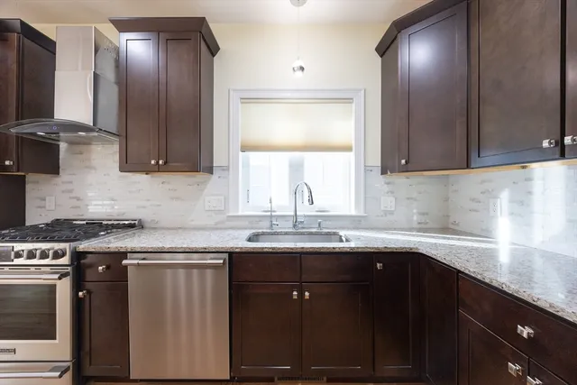 a kitchen with granite countertop stainless steel appliances a sink stove and cabinets