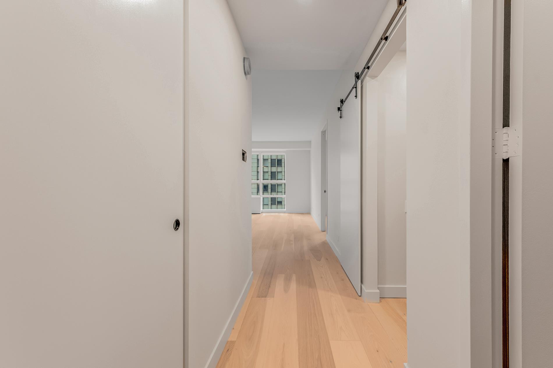 146 West 57th Street, Unit 52E Manhattan, NY 10019 - Photo 18 of 19 a view of a hallway with wooden floor and entryway