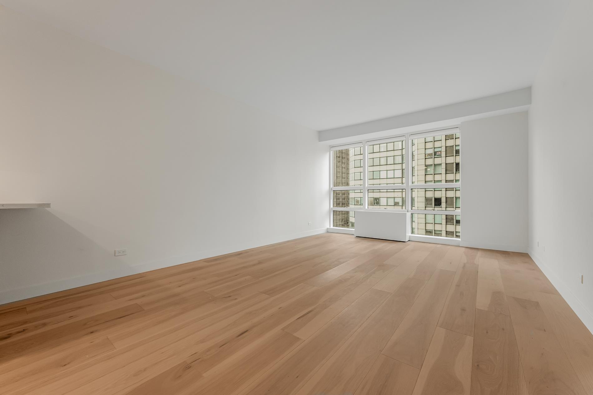 146 West 57th Street, Unit 52E Manhattan, NY 10019 - Photo 3 of 19 wooden floor in an empty room with a window