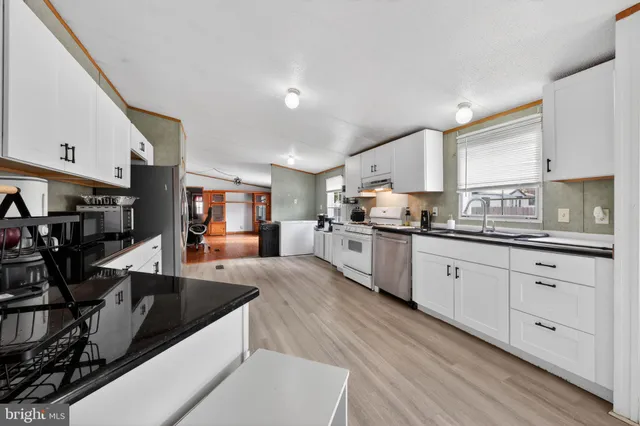 a large kitchen with stainless steel appliances granite countertop a lot of counter space and wooden floors