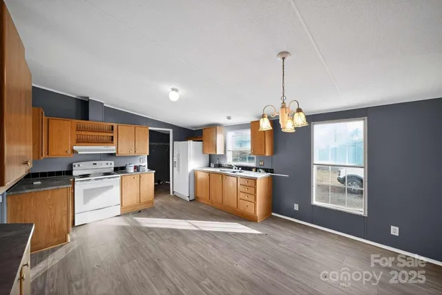 a kitchen with stainless steel appliances granite countertop a stove top oven a sink dishwasher and a refrigerator with wooden floor