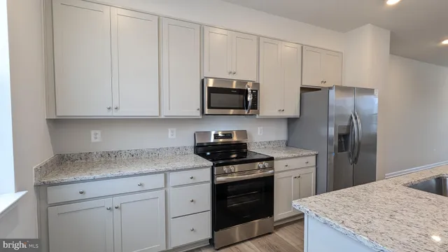 a kitchen with kitchen island granite countertop a sink stove and refrigerator