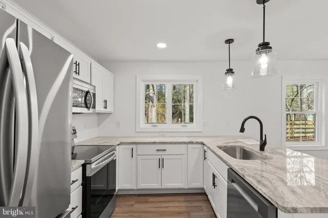 a kitchen with stainless steel appliances granite countertop a sink a stove a refrigerator and island with wooden floor