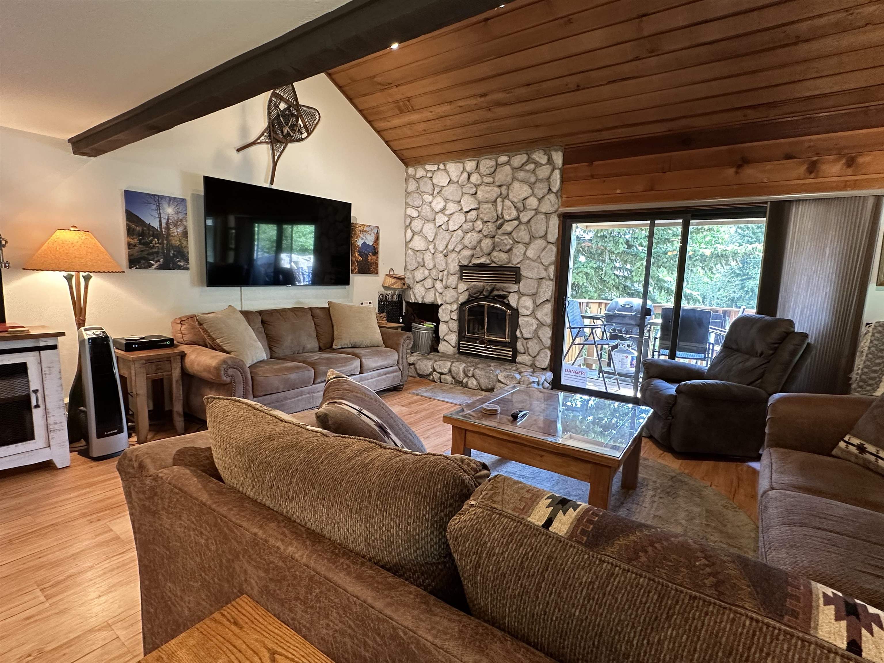 315 Fascination, Unit 315 Mammoth Lakes, CA 93546 - Photo 36 of 44 Living area featuring a stone-clad fireplace, wood-finish flooring, and a vaulted ceiling with exposed beam