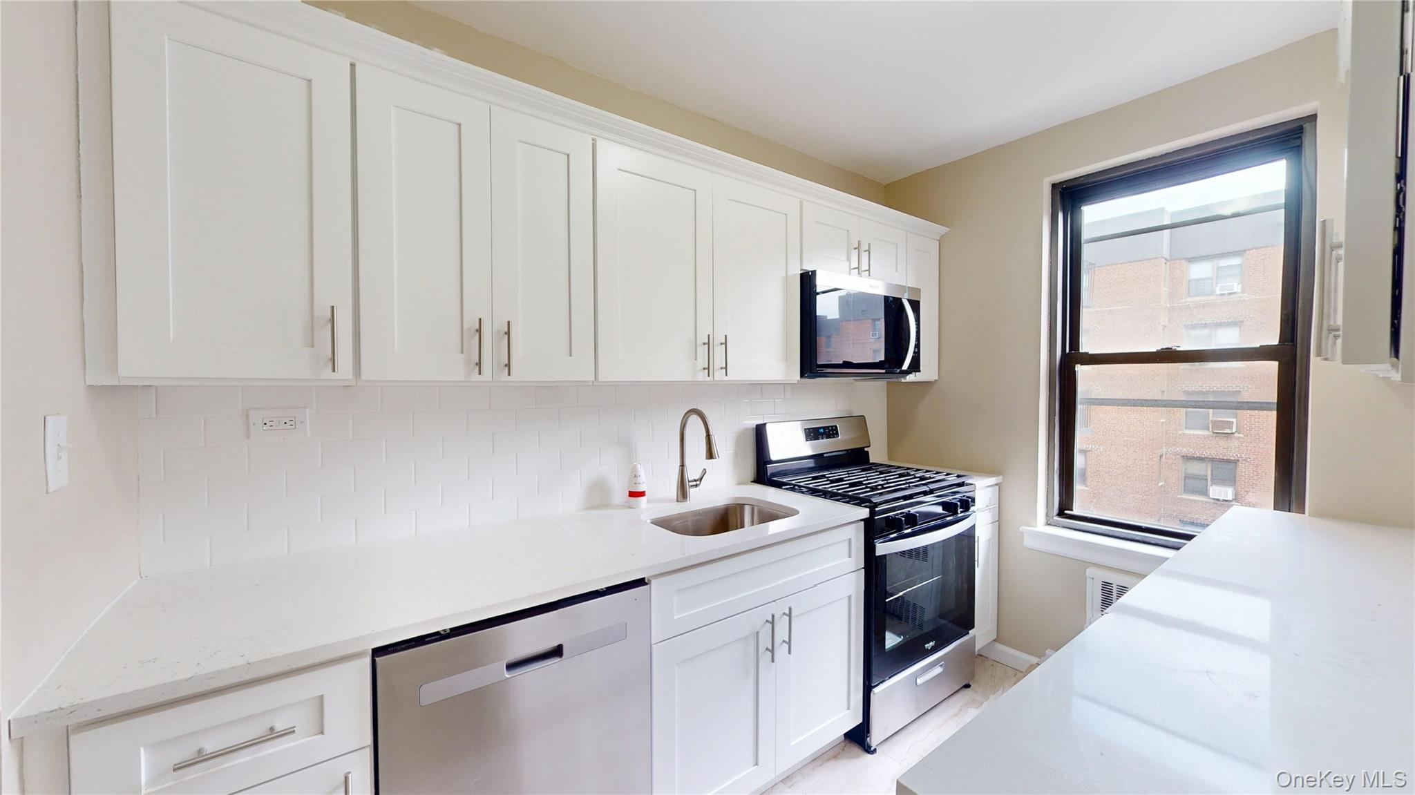 112-30 Northern Boulevard, Unit 4B Queens, NY 11368 - Photo 2 of 12 Kitchen featuring stainless steel appliances, tasteful backsplash, white cabinets, and light stone countertops