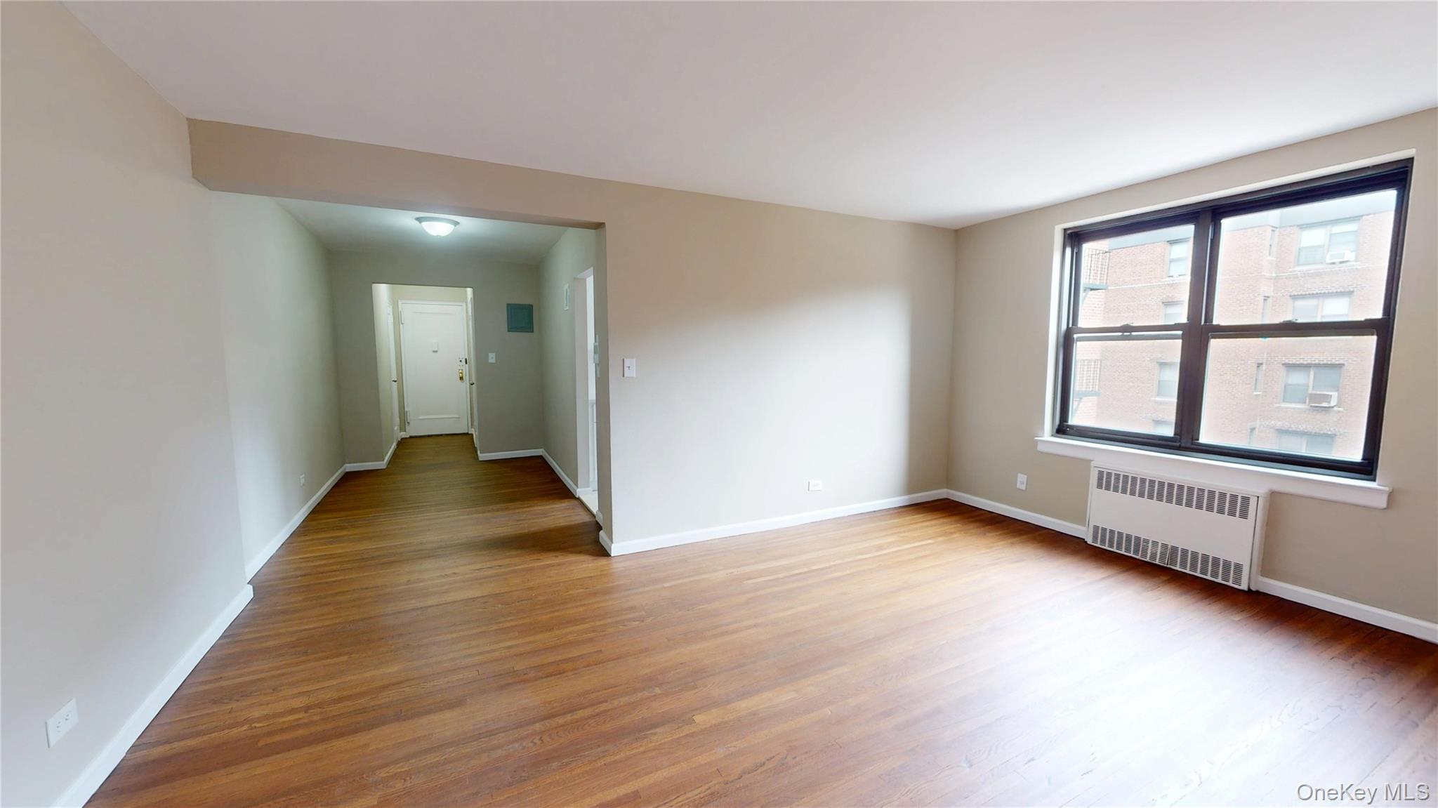 112-30 Northern Boulevard, Unit 4B Queens, NY 11368 - Photo 5 of 12 Empty room featuring radiator and light wood finished floors