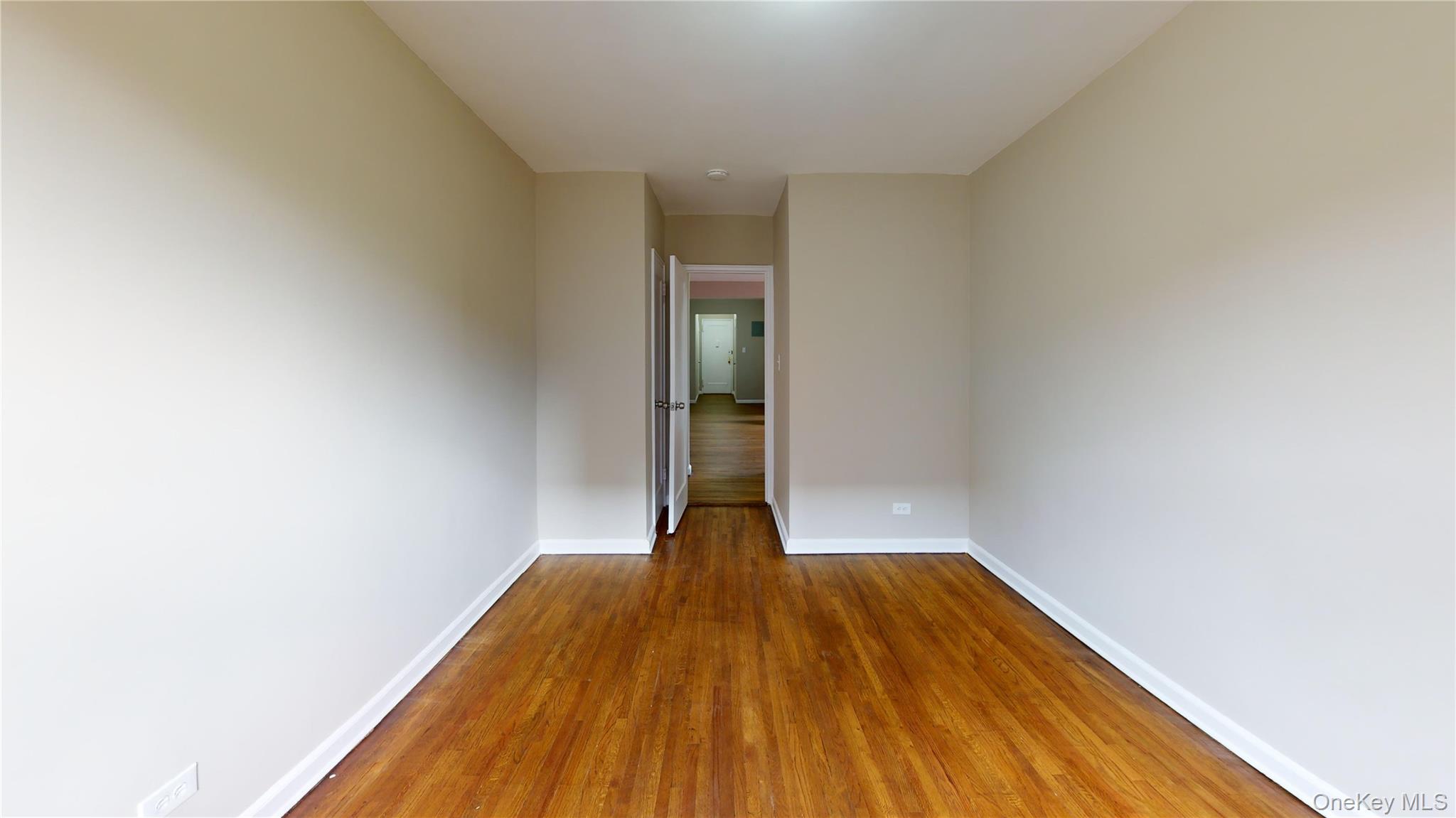 112-30 Northern Boulevard, Unit 4B Queens, NY 11368 - Photo 7 of 12 Empty room with baseboards and dark wood finished floors