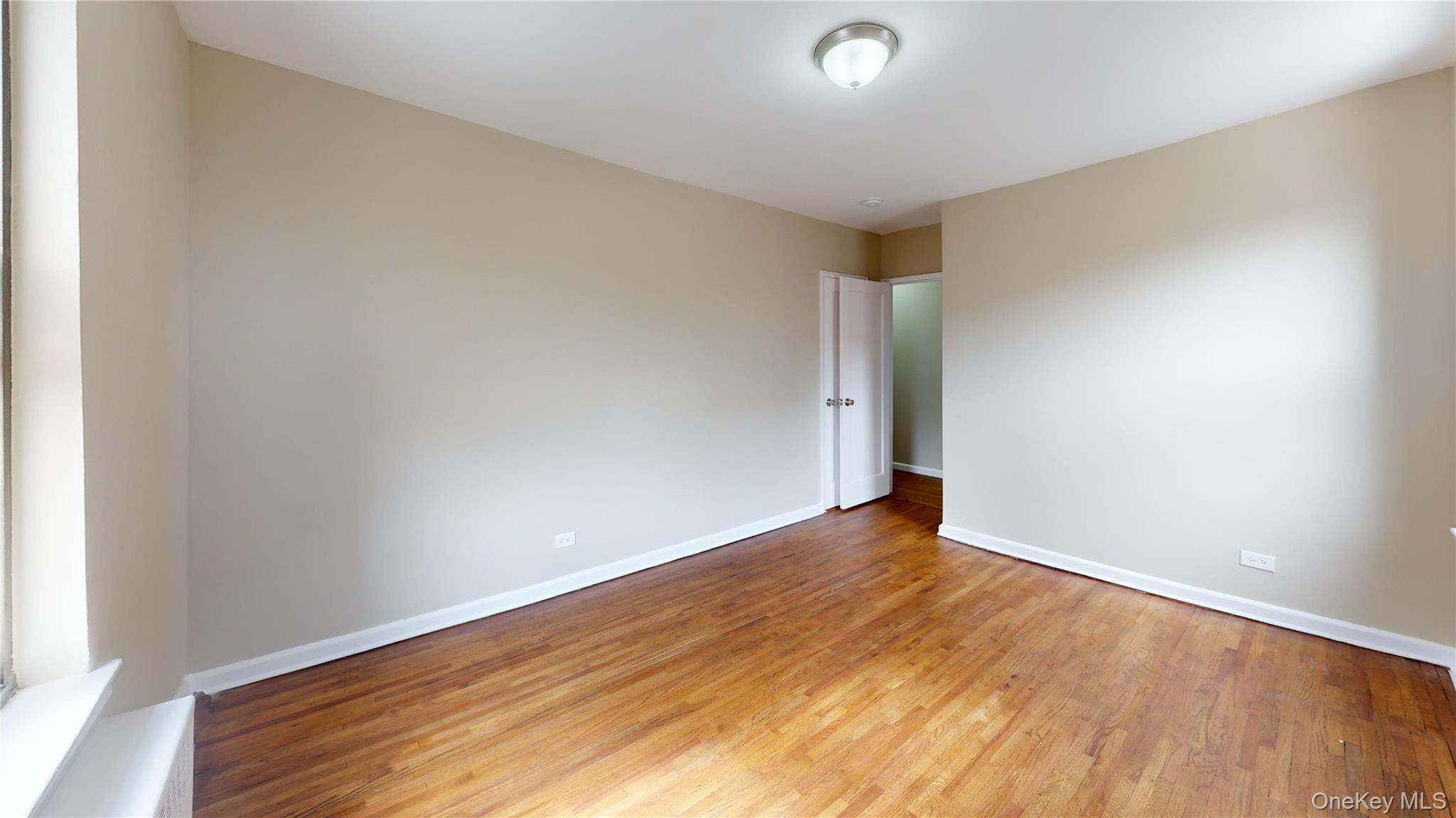 112-30 Northern Boulevard, Unit 4B Queens, NY 11368 - Photo 10 of 12 Unfurnished room featuring light wood-type flooring and baseboards