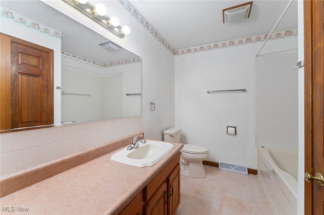 744 Johnson Plank Road Warren, OH 44481 - Photo 20 of 39 Full bath featuring vanity, backsplash, shower / tub combination, and tile patterned flooring