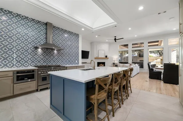 a kitchen with stainless steel appliances kitchen island granite countertop a stove a sink and a refrigerator