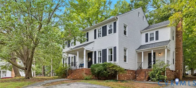 a view of a white house next to a yard with large trees