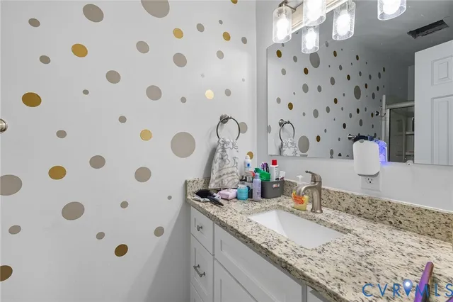 a bathroom with a granite countertop sink a mirror and shower