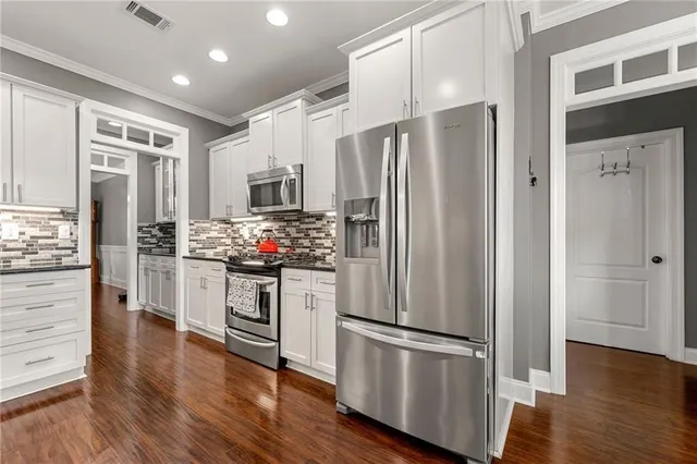 a kitchen with stainless steel appliances a refrigerator stove and wooden floor