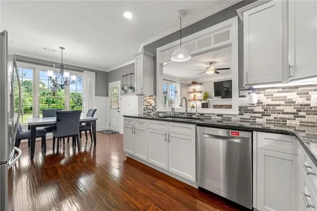 a kitchen with stainless steel appliances granite countertop wooden floor window dining table and chairs