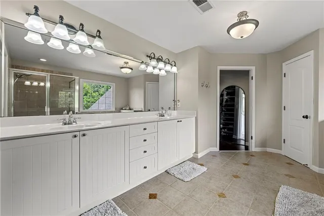 a spacious bathroom with a granite countertop sink a mirror and a shower