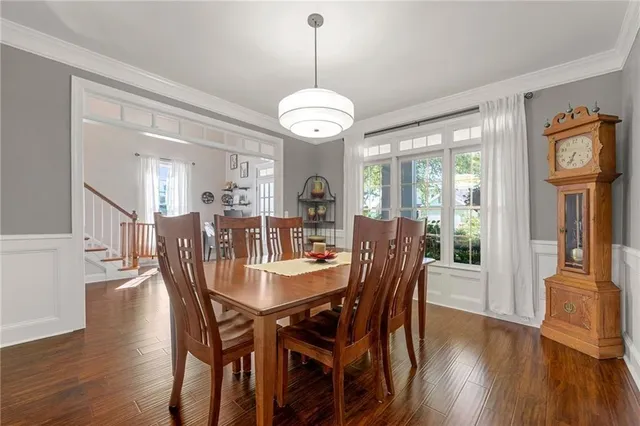a dining room with wooden floor a chandelier a wooden table and chairs