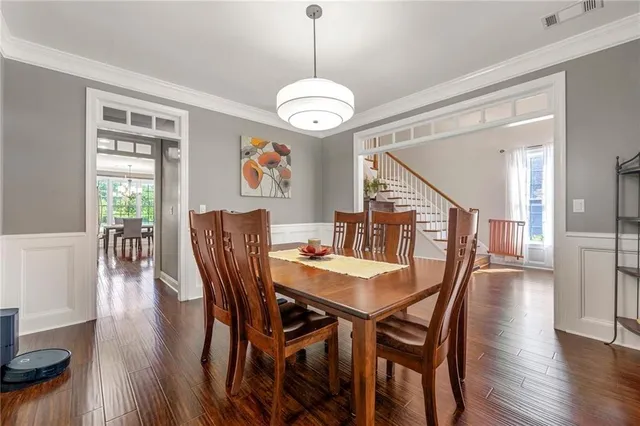 a dining room with wooden floor a chandelier a wooden table and chairs