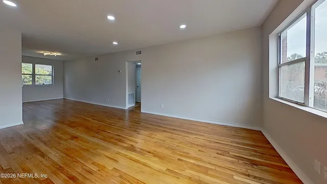 an empty room with wooden floor and windows