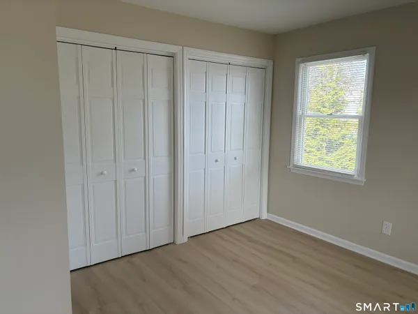 a view of an empty room with closet and a window