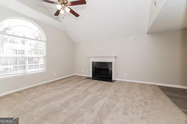 an empty room with windows fireplace and fan