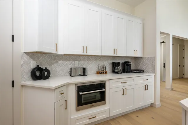 a kitchen with a sink dishwasher stove and white cabinets with wooden floor