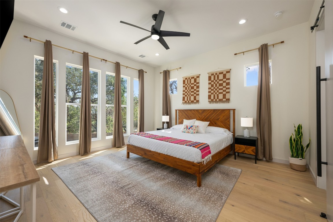 1301 Scenic Circle Spicewood, TX 78669 - Photo 21 of 39 a spacious bedroom with a large bed and a chandelier