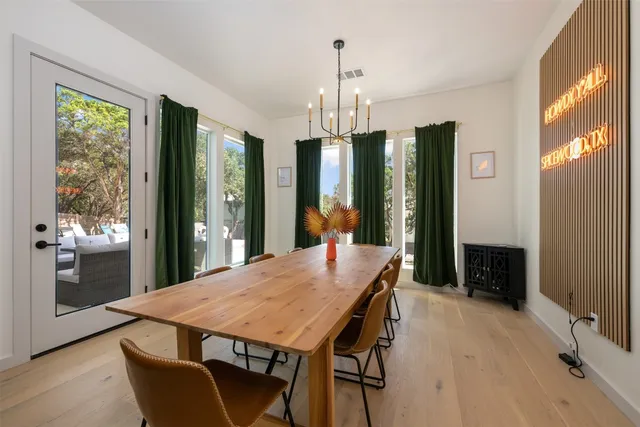 a kitchen with stainless steel appliances kitchen island granite countertop a stove a sink a dining table and chairs with wooden floor