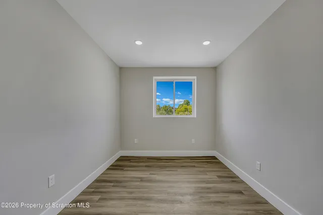 a view of empty room with wooden floor