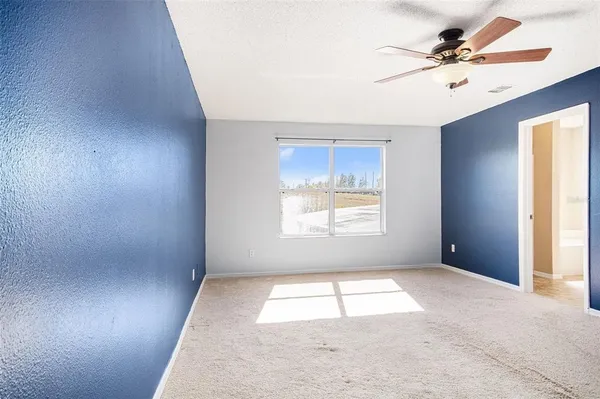 an empty room with windows and fan
