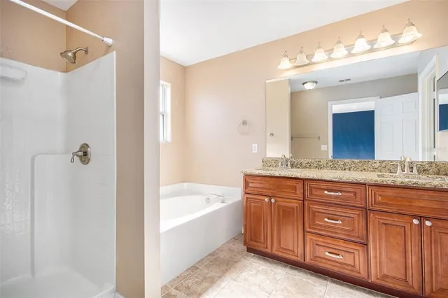 a bathroom with a granite countertop tub sink and mirror
