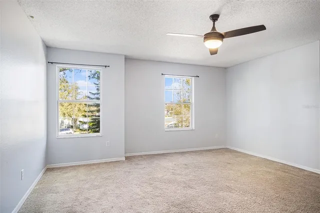 an empty room with a window and a ceiling fan