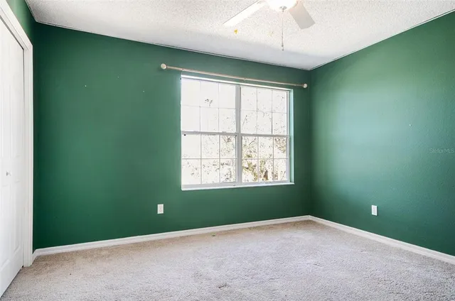 an empty room with a window and a fan