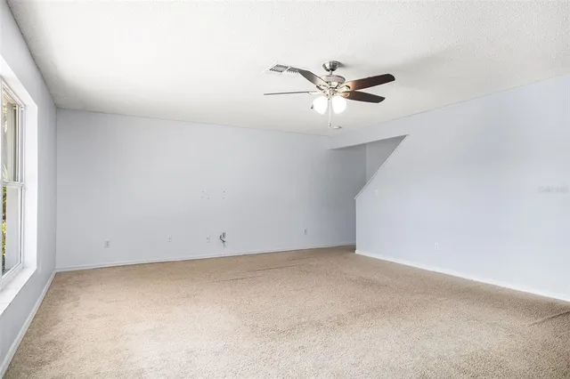 an empty room with a window and a ceiling fan
