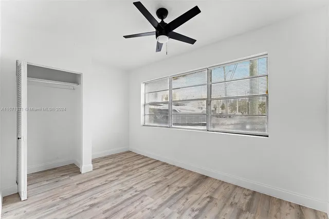 a view of an empty room with a window and wooden floor
