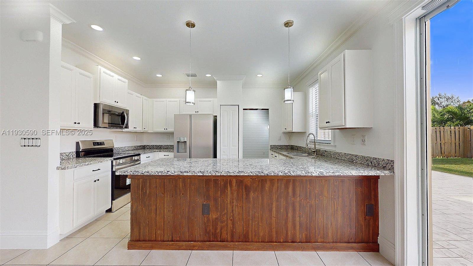 25324 Southwest 119th Avenue Homestead, FL 33032 - Photo 15 of 41 a large kitchen with granite countertop a stove top oven a sink dishwasher and wooden cabinets with wooden floor