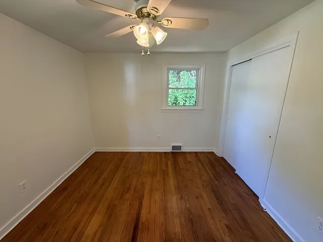 a view of an empty room with wooden floor and a window